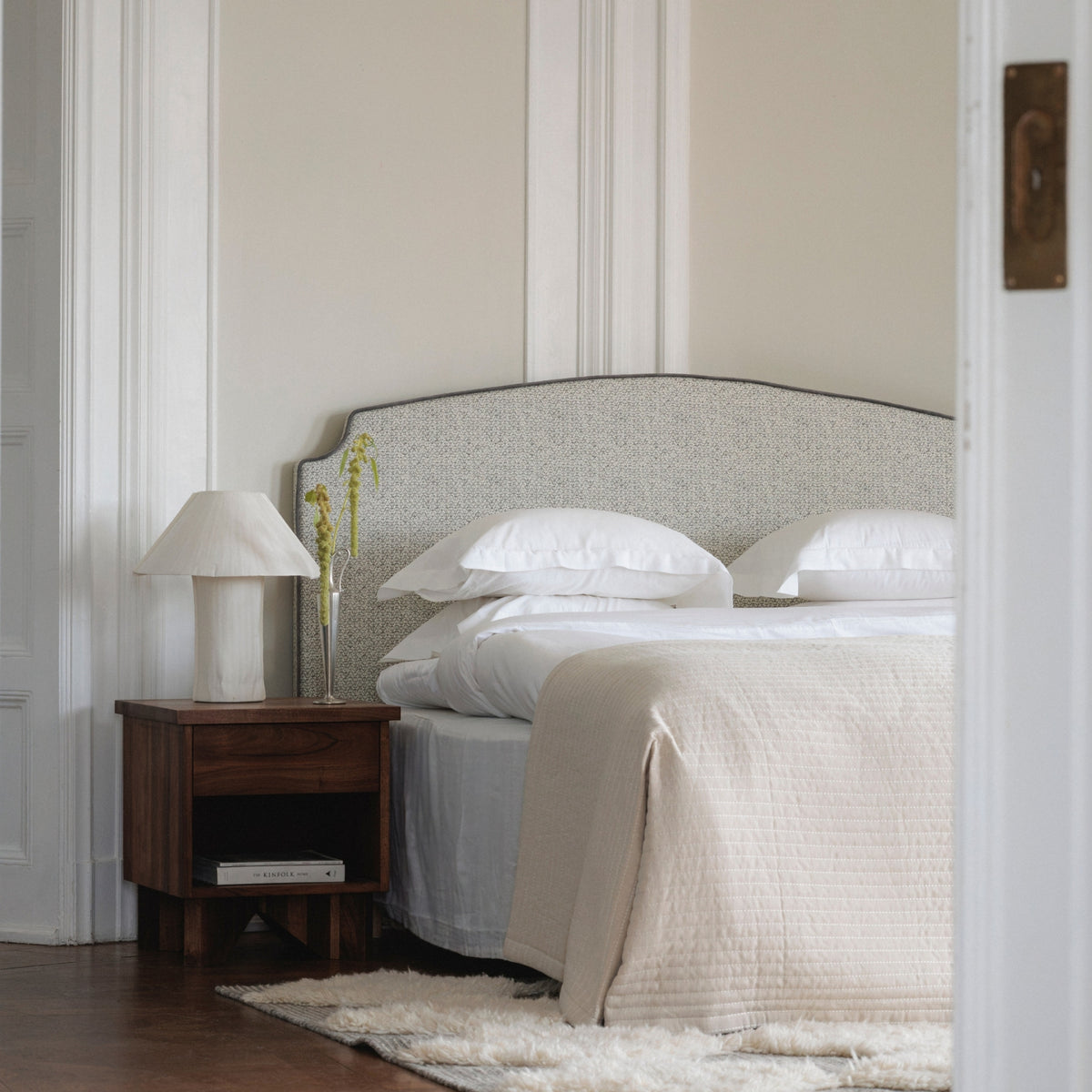 The Residence headboard in Shaded Shale beside a walnut nightstand, Snow White bedding