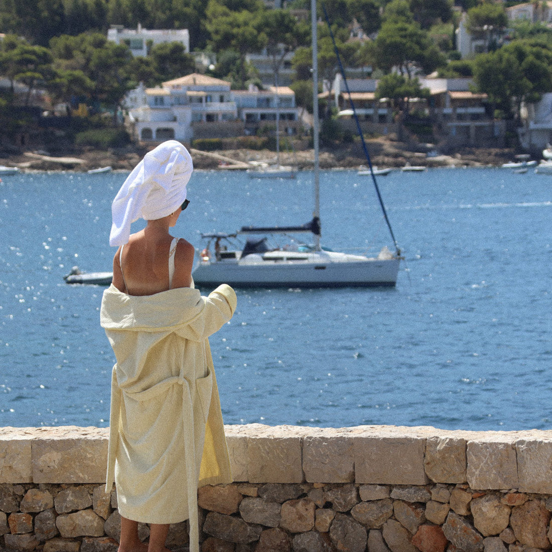 A woman in a Juniper robe and towel looking out over the sea