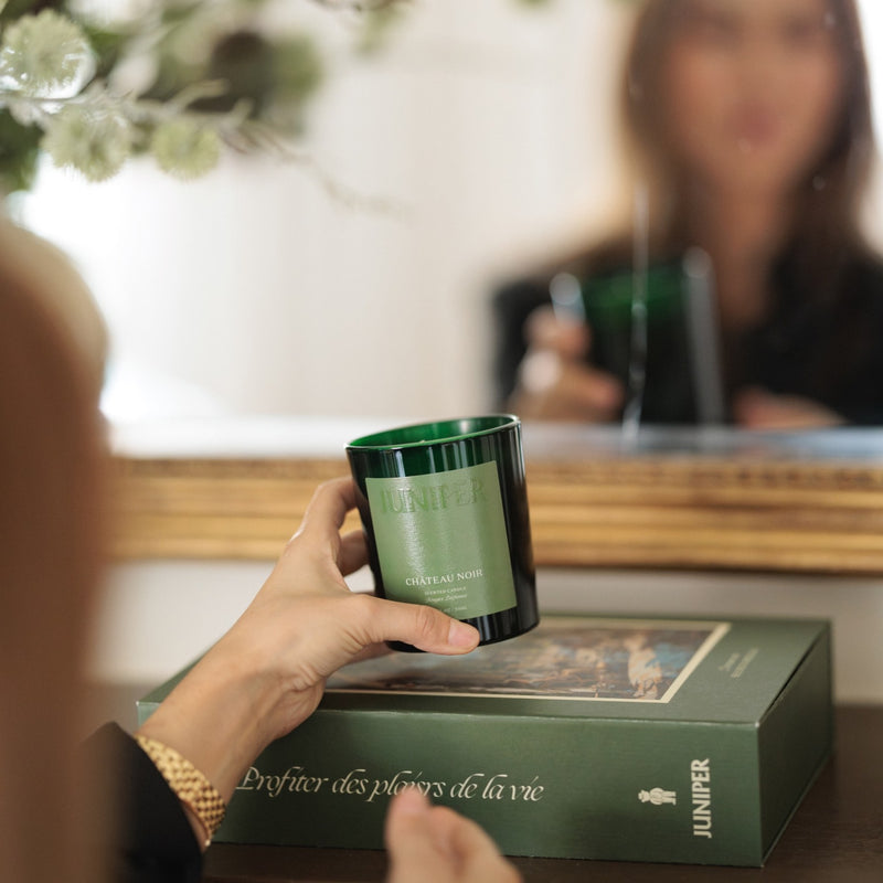 Château Noir scented candle held in front of a mirror