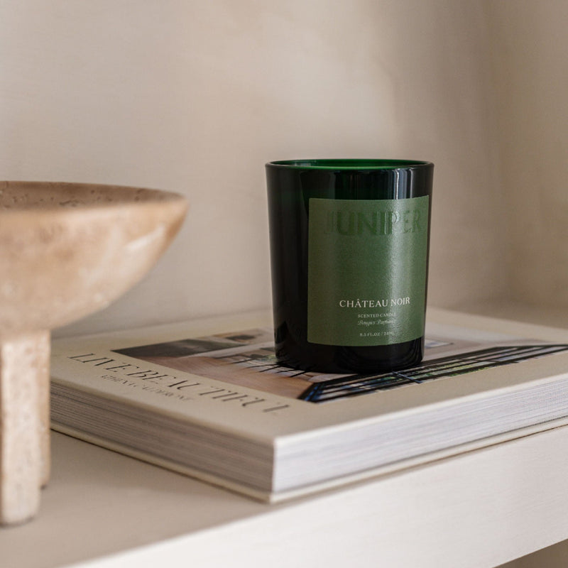 Château Noir scented candle on a stack of magazines